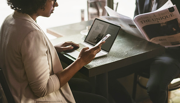 woman at computer looking at phone