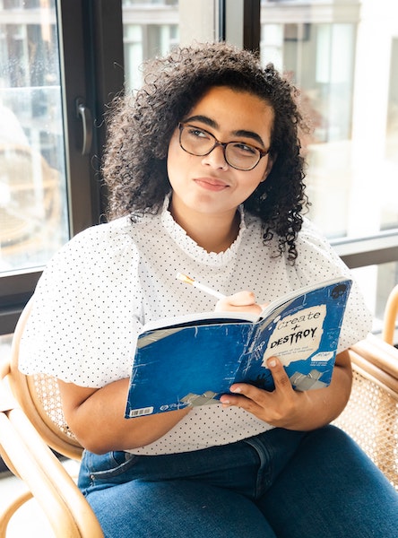 Woman Pondering While Writing in Notebook