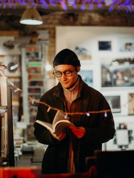 Man Flipping Through Book in Bookstore