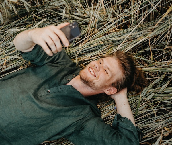 Man Laying on Grass Talking on Phone Video Chat