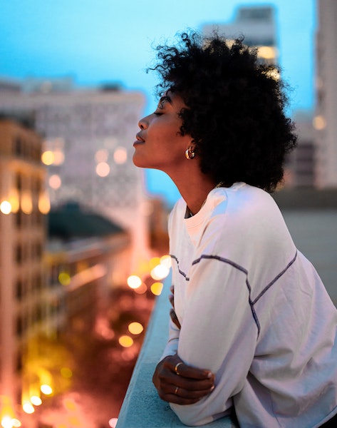 Woman Gazing While Standing on City Balcony