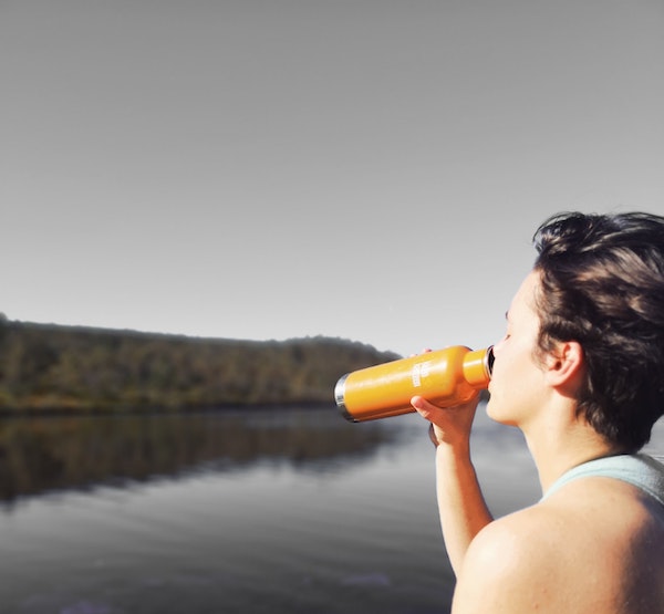 Person Drinking Water Overlooking a Lake