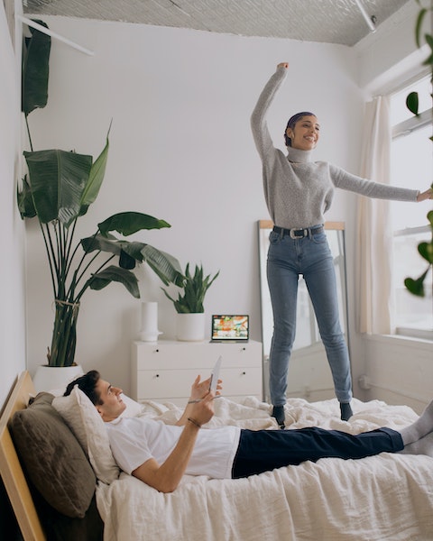 Woman Jumping on Bed with Partner
