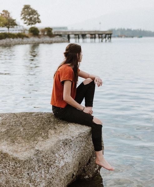 Woman Sitting on Rock Gazing at Peaceful Water