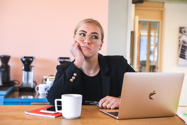 Woman Shrugging and Thinking at Computer Desk