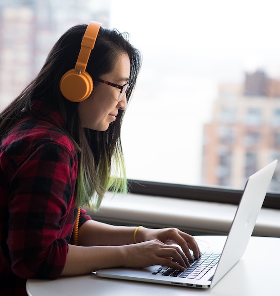 Woman Looking at Computer While Wearing Headphones
