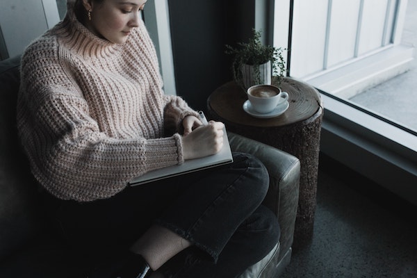 Woman Sitting on Couch While Writing in Journal