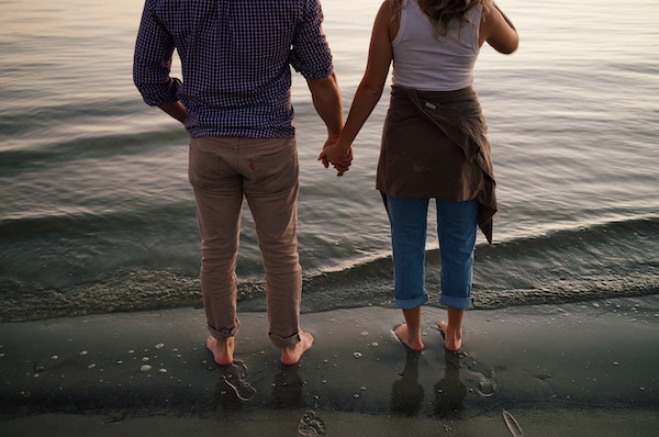 Bare Foot Couple Holding Hands While Walking on the Sand