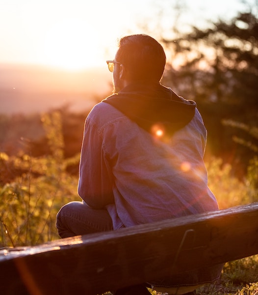 Man Sitting on Park Bench Looking at Sunset