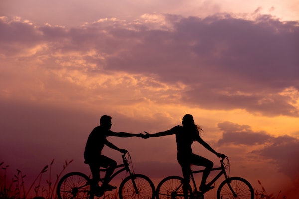 Couple Reaching for Each Others Hands While Biking