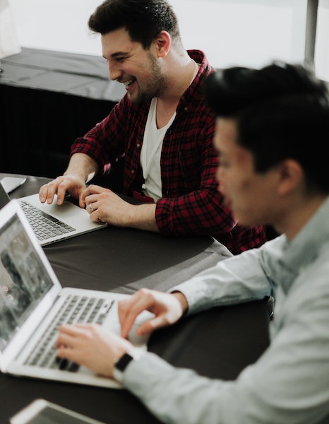 Men Chatting and Smiling While Working on Computers