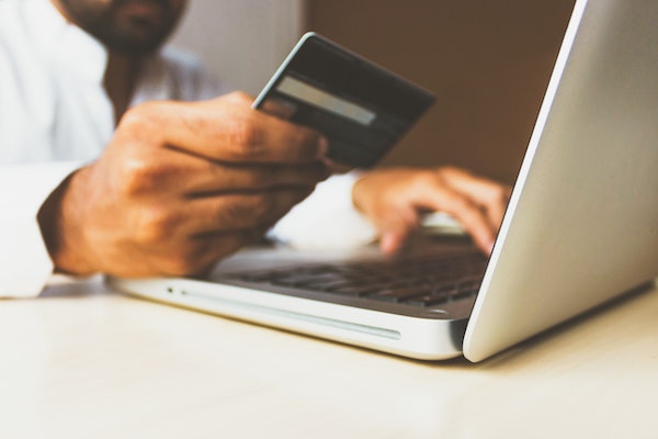 Man Holding Credit Card While Looking at Computer