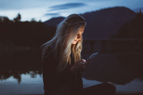 Woman Looking at Phone Outside in the Evening