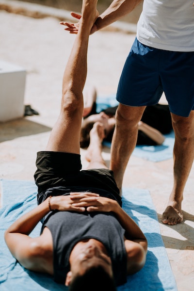 Man Stretching With Assistance of Instructor