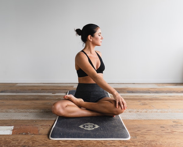Woman Sitting on Yoga Mat Performing Torso Stretch