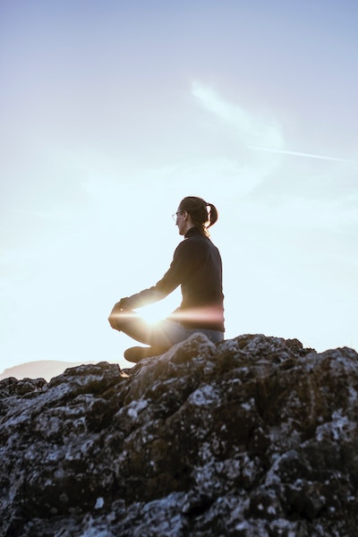 Woman Sitting on Rock Overlooking Landscape