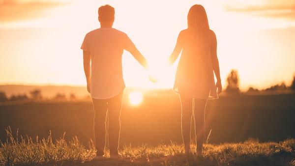 Two People Holding Hands Looking at Sunset