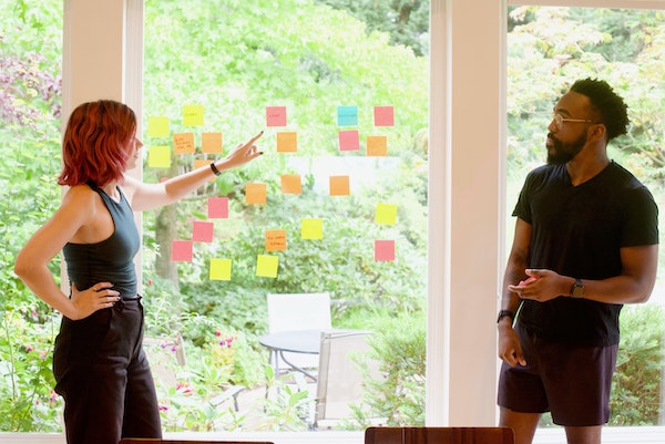 Man And Women Looking at Post-it Notes On Board