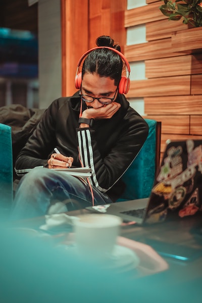 Man Listening to Music Through Headphones While Journaling