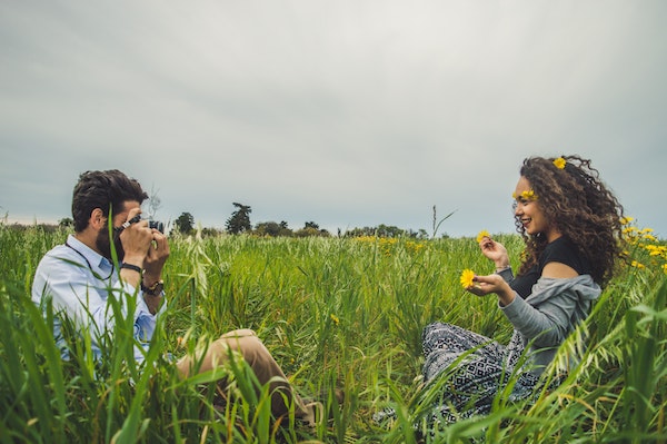 Man Taking Photo of His Partner in Grassy Field