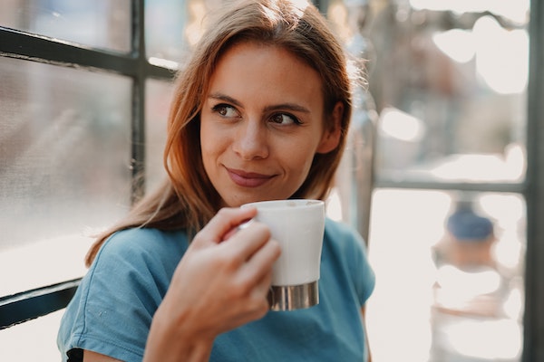 Woman Looking Out Window While Enjoying Coffee