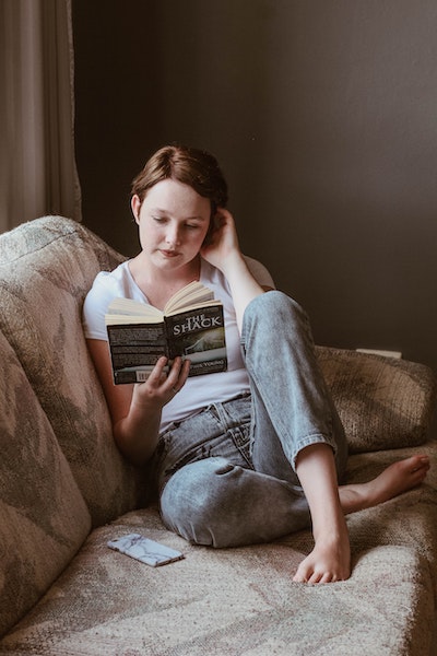 Woman Sitting on Couch Reading a Book