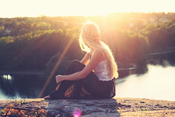 Woman Sitting on Cliff Overlooking Vast Seascape